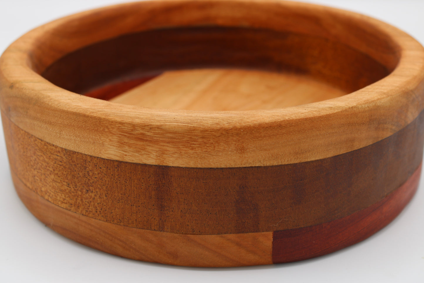 A round wooden bowl with a multi-layered inlay design featuring natural, medium, and reddish-brown wood tones, shown on a plain white background.