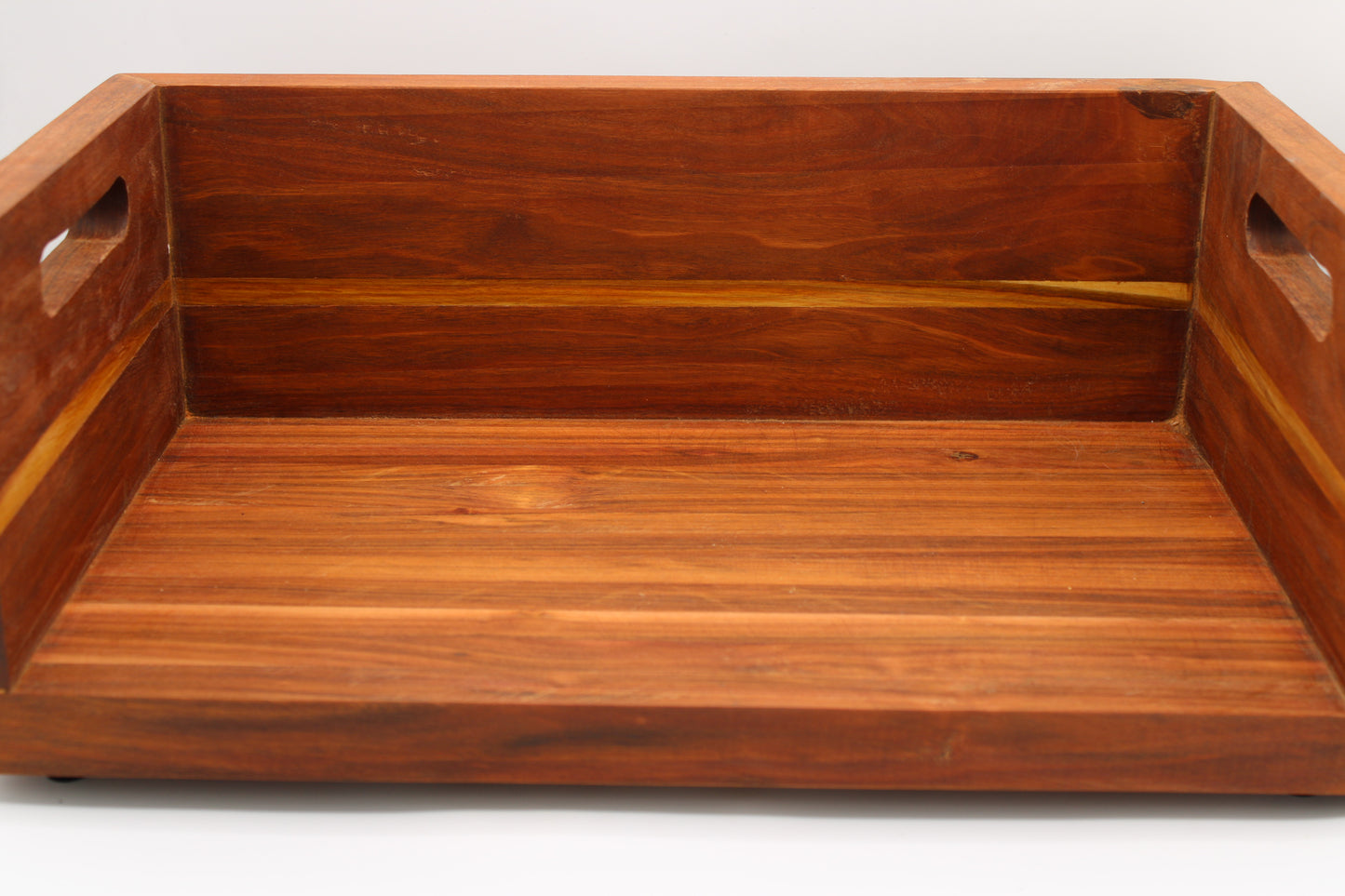 A rectangular wooden serving tray with a warm reddish-brown finish and cutout handles on the sides, shown against a plain white background.
