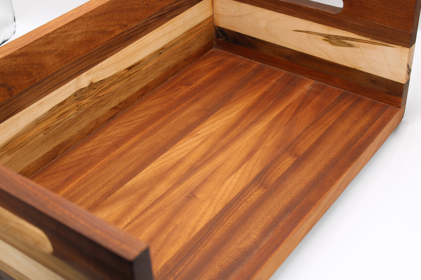 Close-up of a wooden tray or basket with a warm medium-brown stained interior and lighter natural wood edges, photographed on a white background.