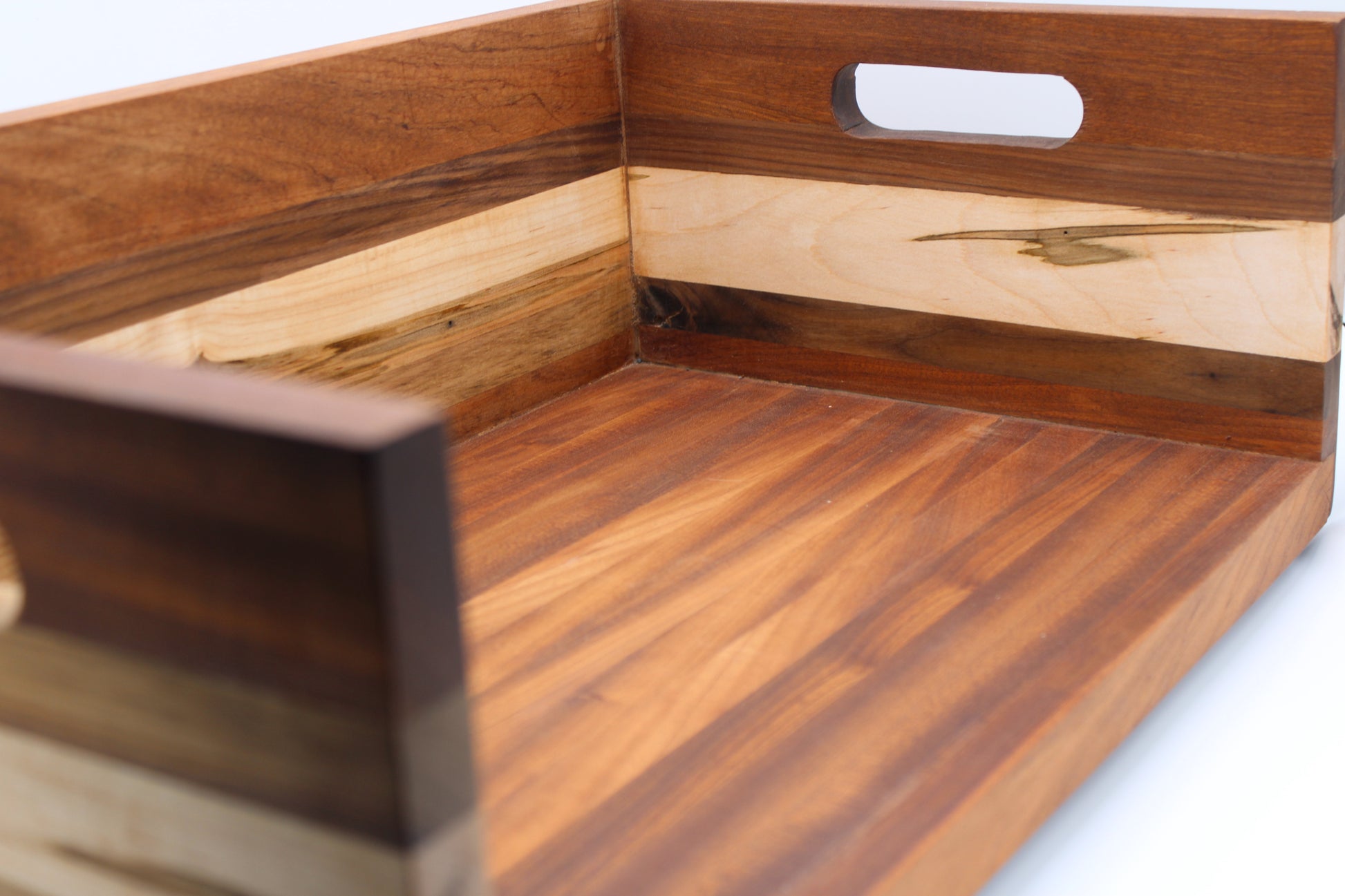 A close-up of a wooden serving tray with a handle cutout, featuring alternating dark and light wood grain panels on a white background.