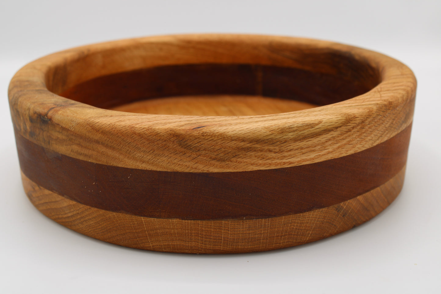 A handmade wooden bowl with a natural light brown wood exterior, a dark brown wood inlay band, and a lighter brown wood interior, shown on a plain white background.