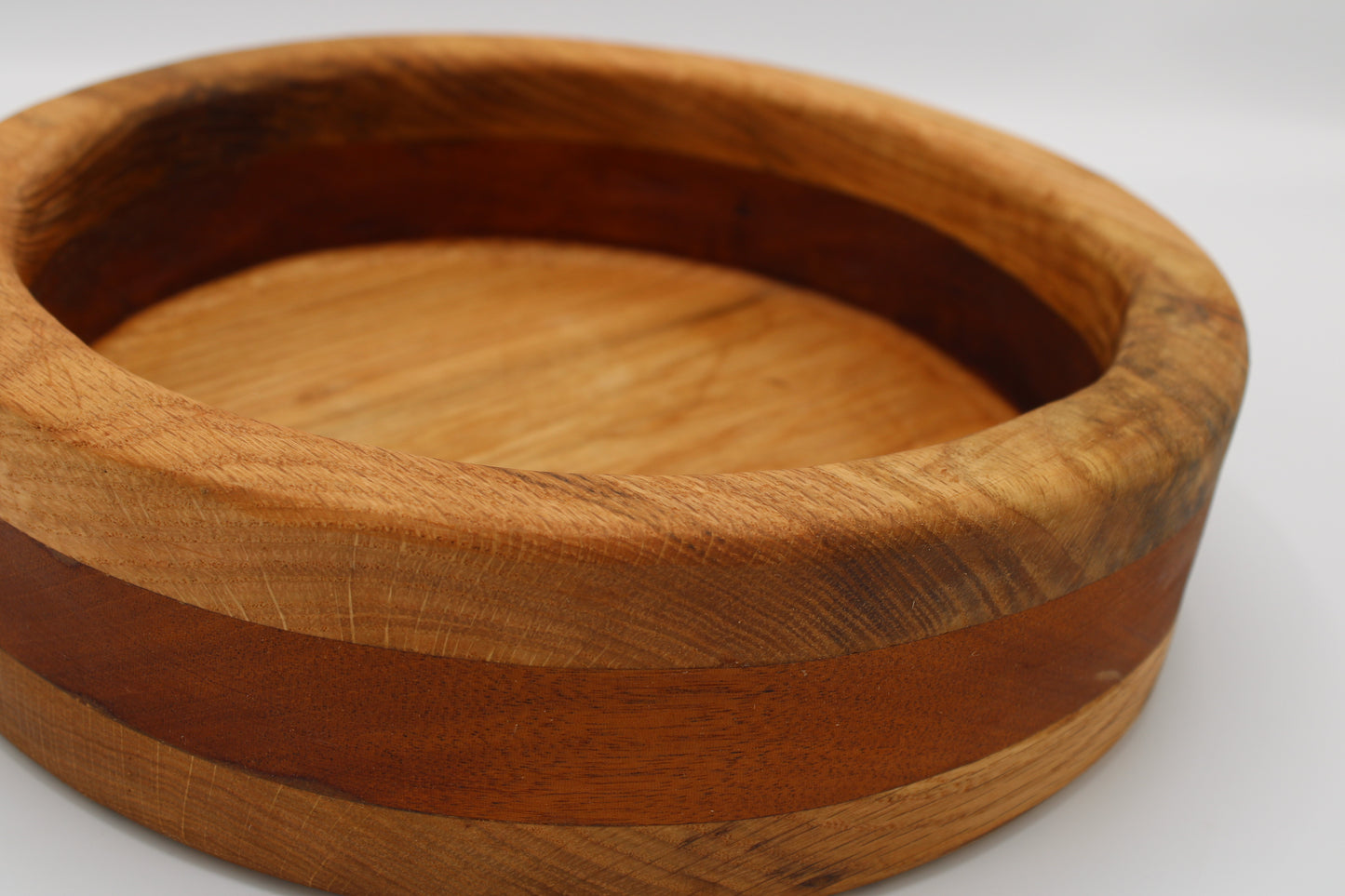 A round wooden bowl with a natural wood grain finish and a darker brown inlay band, shown on a plain white background.