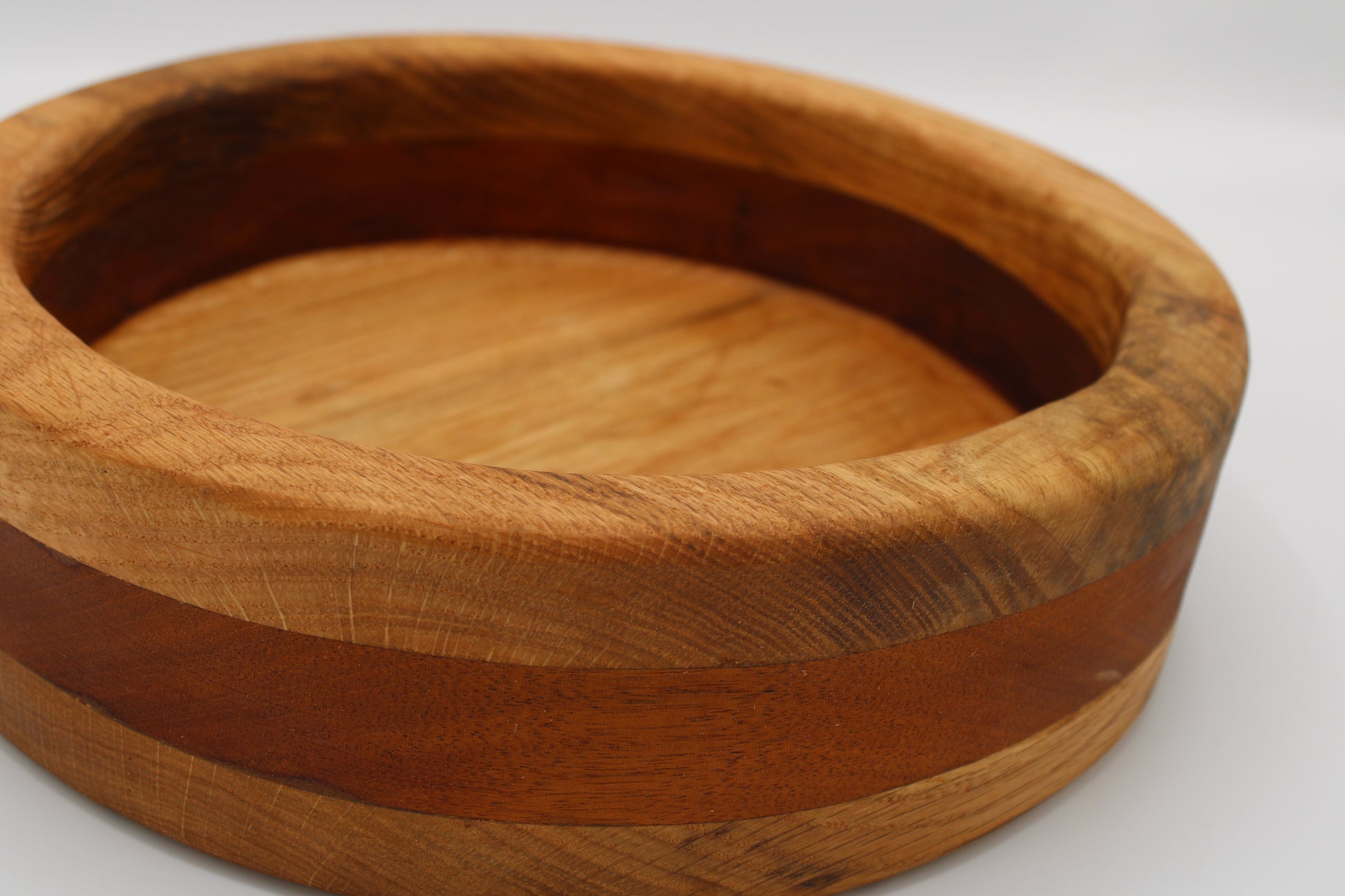 A round wooden bowl with a natural wood grain finish and a darker brown inlay band, shown on a plain white background.