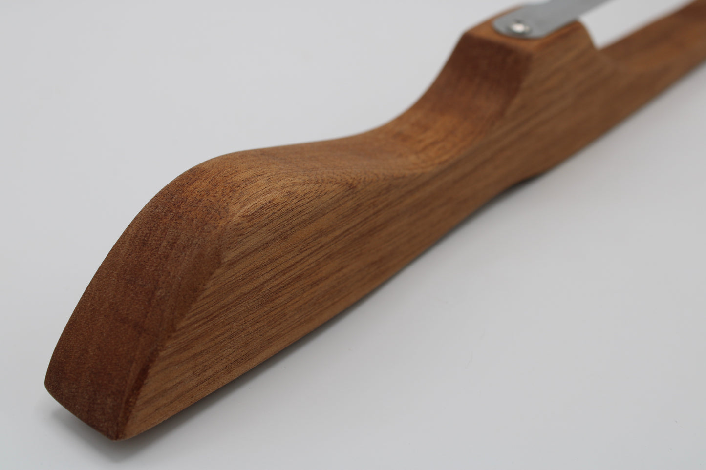 A close-up of a wooden knife handle with a rich medium-brown wood grain, featuring a silver metal bolster screw, set against a plain light gray background.