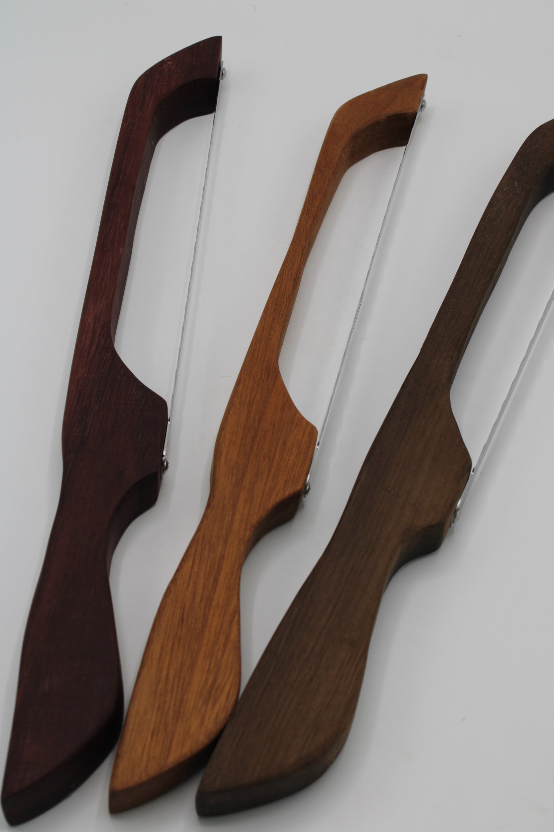 Three wooden bowfishing arrows with different wood grain finishes (dark reddish-brown, medium brown, and dark brown) with silver steel shafts, displayed diagonally on a light gray background.