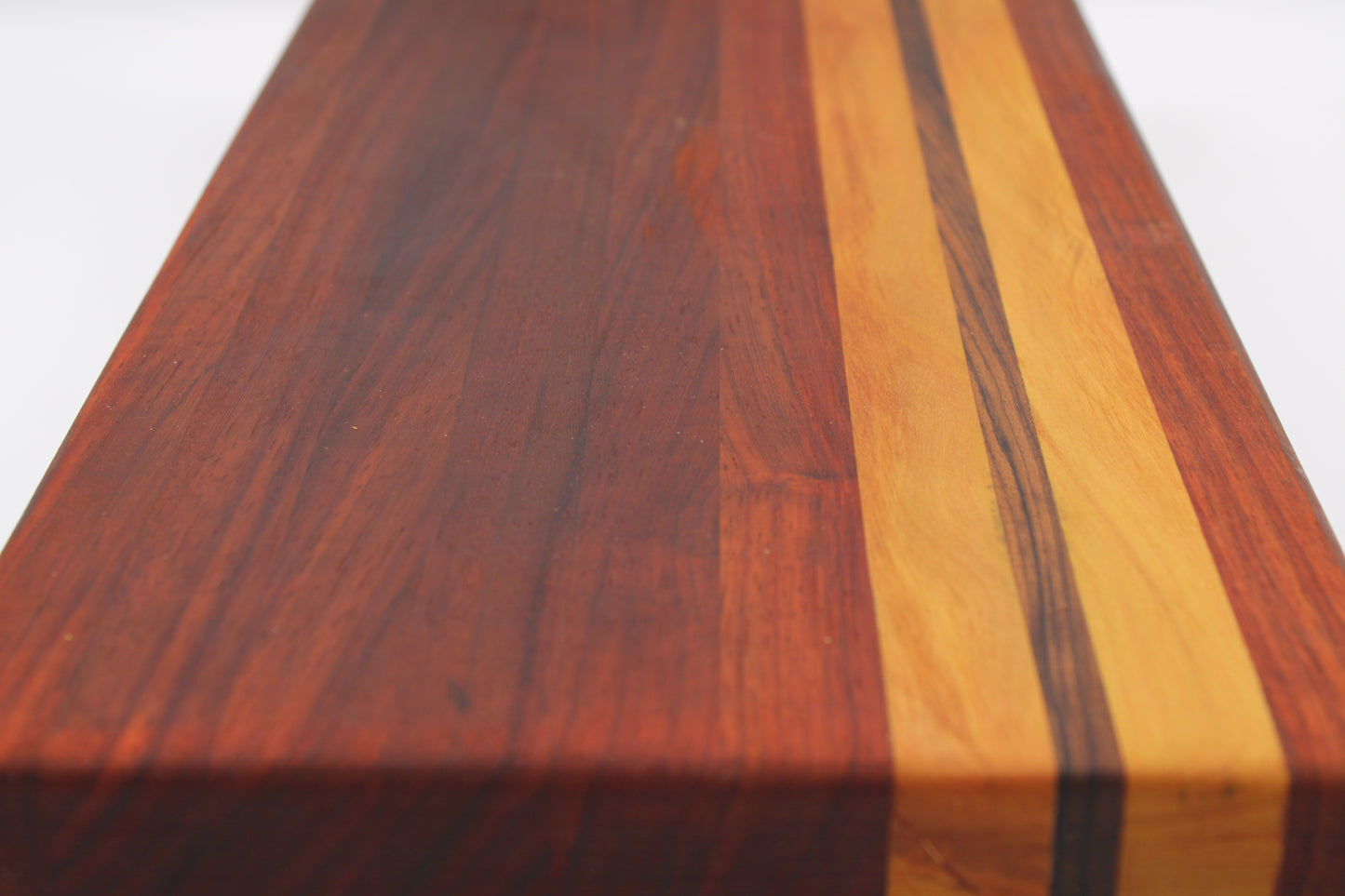 A close-up of a wooden board or block with a dark reddish-brown wood grain face and two light tan wood inlay stripes, photographed against a plain white background.