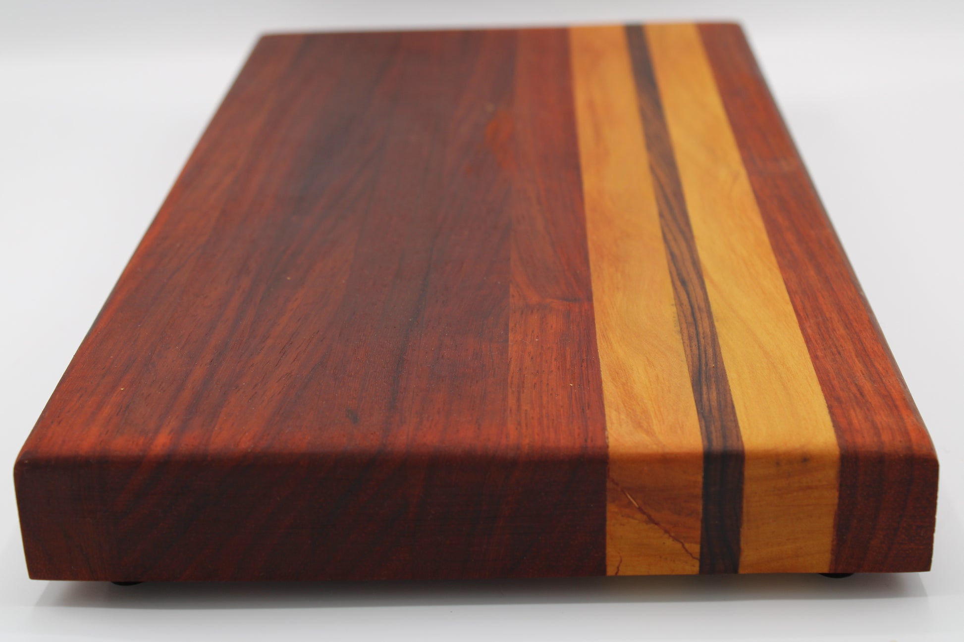 A rectangular wooden cutting board with a rich reddish-brown mahogany finish and two vertical inlay stripes of contrasting light and dark wood, shown on a white background.
