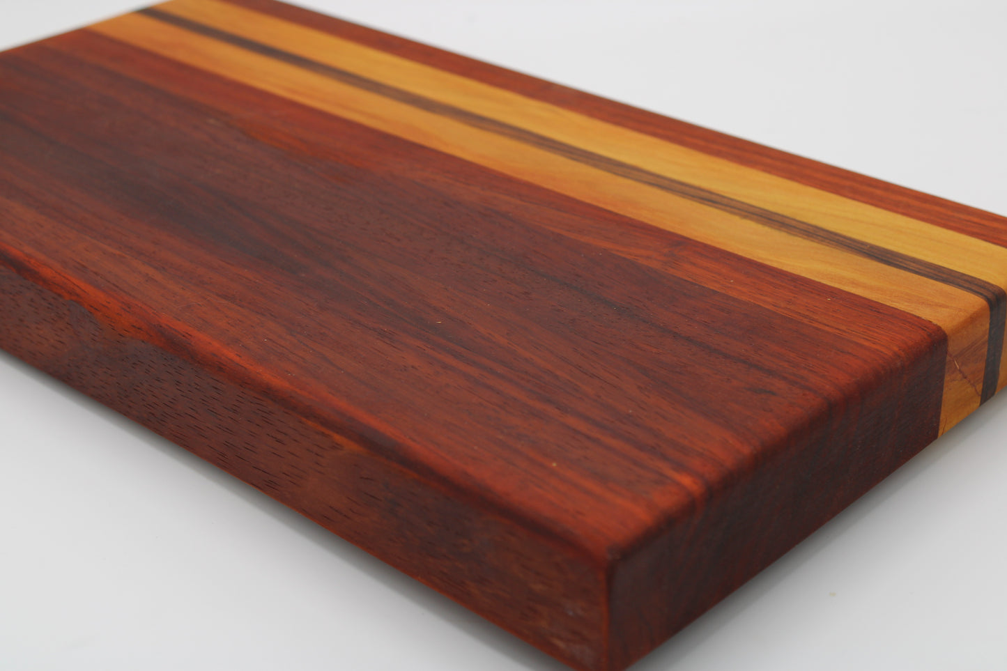 A rectangular wooden cutting board with a rich reddish-brown wood grain and decorative stripes of light and dark wood inlay, shown on a plain white background.