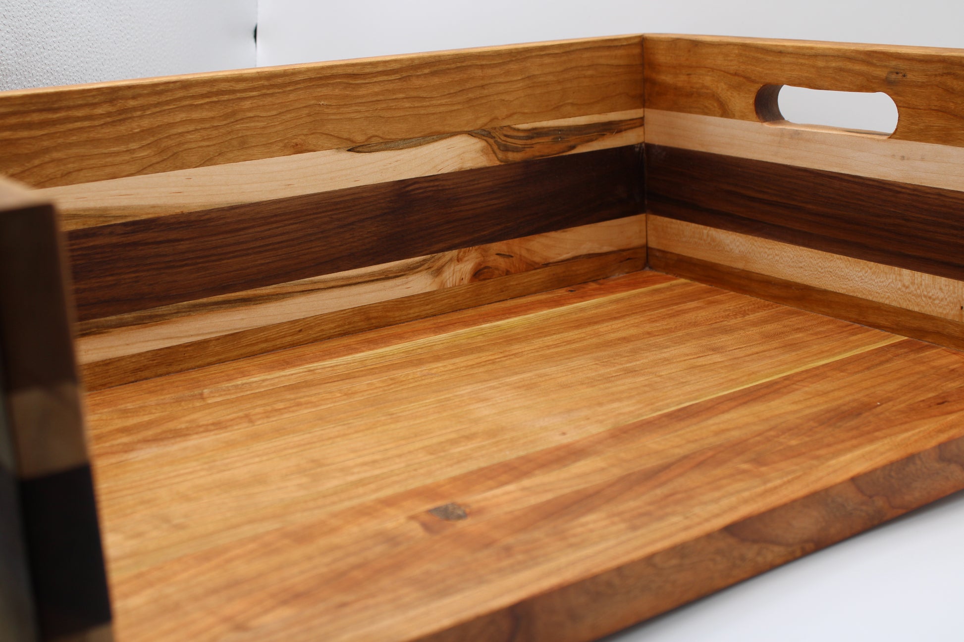 A close-up of a BBQ Chopping Box with a warm honey finish and dark wood inlay, featuring a cutout handle on the side.