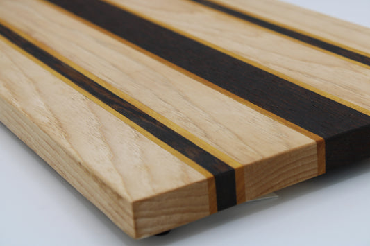 Striped wooden cutting board with light, dark and orange stripes